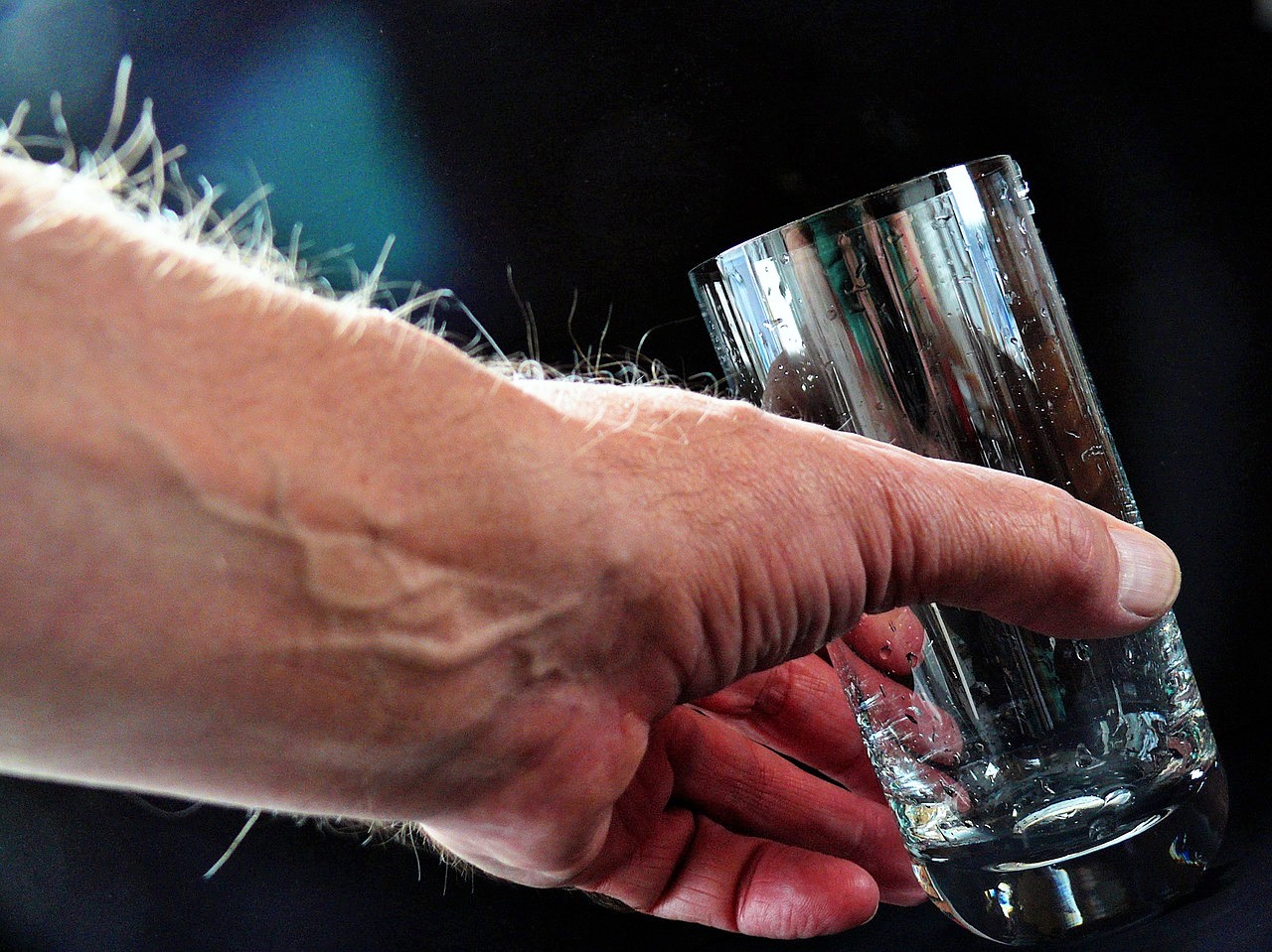 Протиевая вода. Рука с бокалом. Стакан воды в руке. Стакан воды на ладони. Мужик в руках стакан воды.